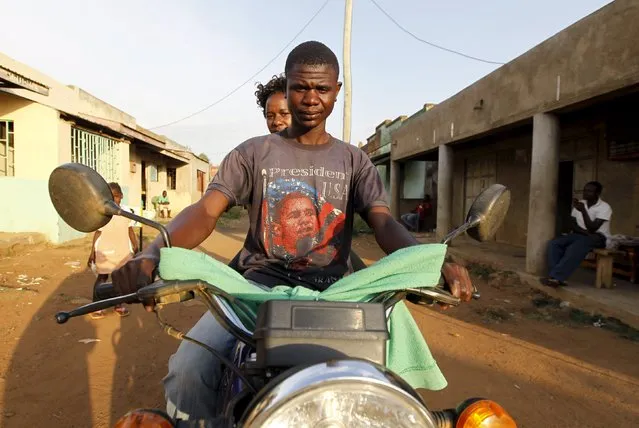 A motorcyclist taxi-driver wearing a T-shirt with the image of U.S. President Barack Obama carries a passenger at the trading centre in the village of Kogelo, west of Kenya's capital Nairobi, July 15, 2015. (Photo by Thomas Mukoya/Reuters)