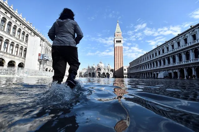 A woman walks at the flooded St. Mark's Square during a period of seasonal high water in Venice, November 14, 2019. (Photo by Flavio Lo Scalzo/Reuters)