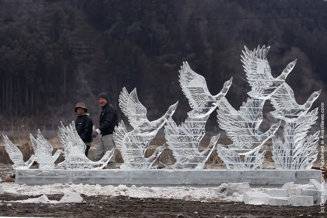 Two men walk past an ice scultpture carved for the anniversary of last year's deadly earthquake and tsunami on March 11, 2012 in Rikuzentakata, Japan