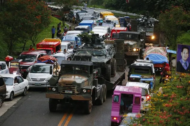 A damaged Armored Personnel Carrier is transported for repair as a queue of vehicles with fleeing residents that stretches for miles (kilometers) following the siege by Muslim militants in Marawi city in southern Philippines Thursday, May 25, 2017. Army tanks packed with soldiers rolled into the southern Philippine city Thursday to try to restore control after ISIS-linked militants launched a violent siege that sent thousands of people fleeing for their lives and raised fears of extremists gaining traction in the country. (Photo by Bullit Marquez/AP Photo)