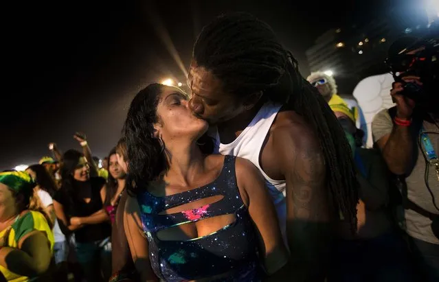 A couple share a celebratory kiss after watching Brazil score a goal its second goal, during the FIFA Fan Fest on Copacabana beach in Rio de Janeiro. (Photo by Silvia Izquierdo/Associated Press)