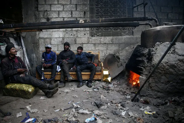 Abu Fahad (2nd R) rests with colleges inside a workshop in the rebel-held besieged Douma neighbourhood of Damascus, Syria April 1, 2017. The workshop uses plastic from bottles and other waste materials to produce liquid and gas fuels.The liquid is refined into gasoline, diesel and benzene fuels which are sold for domestic and commercial use. (Photo by Bassam Khabieh/Reuters)