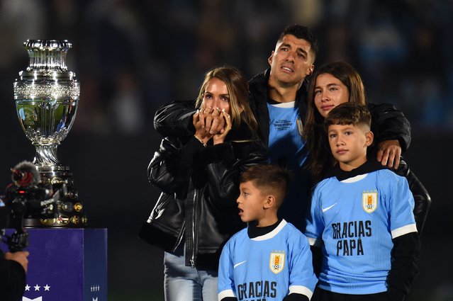 Uruguay's forward Luis Suarez (C) reacts next to his wife Sofia Balbi (L) and their children Delfina (R), Lautaro (C), and Benjamin, next to a replica of the Copa America he was presented during his farewell ceremony to the national team after the 2026 FIFA World Cup South American qualifiers football match between Uruguay and Paraguay at the Centenario stadium in Montevideo, on September 6, 2024. (Photo by Dante Fernandez/AFP Photo)