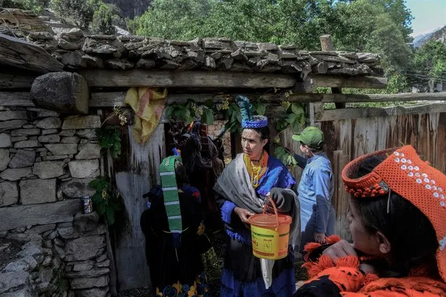 Kalash tribe women wearing a traditional dress walk towards their relative's house to collect milk and dance as a part of ritual on the first day of “Joshi” festival to welcome the arrival of spring at Bumburet village in northern Pakistan on May 14, 2022. (Photo by Abdul Majeed/AFP Photo)