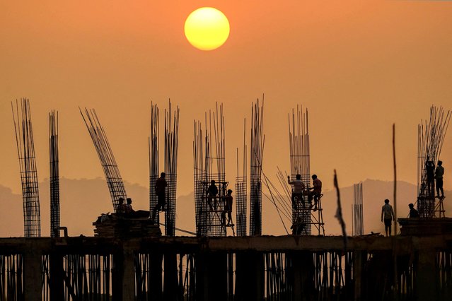 Workers are silhouetted against the setting sun at a construction site in Pushkar, India on September 18, 2024. (Photo by Himanshu Sharma/AFP Photo)