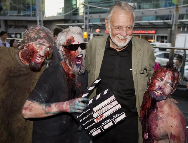 In this September 12, 2009, file photo, director George Romero poses with some fans dressed as zombies after accepting a special award during the Toronto International Film Festival in Toronto. Romero, whose classic “Night of the Living Dead” and other horror films turned zombie movies into social commentaries and who saw his flesh-devouring undead spawn countless imitators, remakes and homages, has died. He was 77. Romero died Sunday, July 16, 2017, following a battle with lung cancer, said his family in a statement provided by his manager Chris Roe. (Photo by Darren Calabrese/The Canadian Press via AP Photo)