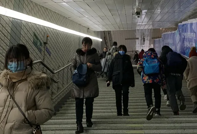 People wearing masks walk down the steps at a subway station in Beijing, China on January 21, 2020. (Photo by Tingshu Wang/Reuters)