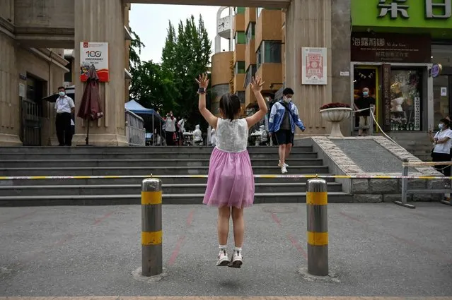 A girl waits for her sister outside school premises after finishing the first day of the National College Entrance Examination (NCEE), known as “Gaokao”, in Beijing on June 7, 2022. (Photo by Jade Gao/AFP Photo)
