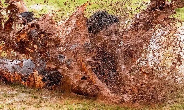 A boy dives in a puddle of muddy water as he enjoys the rains in Mumbai, India, Monday, June 27, 2022. (Photo by Rajanish Kakade/AP Photo)