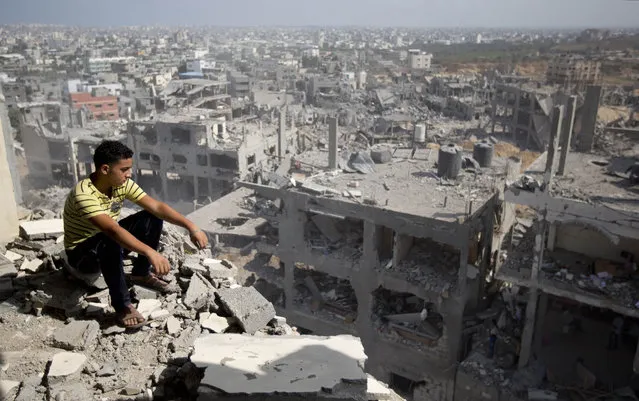 A Palestinian man looks out over destruction in part of Gaza City's al-Tufah neighbourhood as the fragile ceasefire in the Gaza Strip entered a second day on August 6, 2014 while Israeli and Palestinian delegations prepared for crunch talks in Cairo to try to extend the 72-hour truce. The ceasefire, which came into effect on August 5, has brought relief to both sides after one month of fighting killed 1,875 Palestinians and 67 people on the Israeli side. (Photo by Mahmud Hams/AFP Photo)