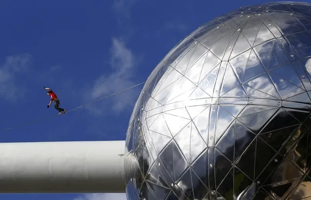 A tightrope walker performs between two spheres of the Atomium monument in Brussels August 11, 2014. The 102-metre-tall (335-feet-tall) structure and its nine spheres, which was designed for Expo 58, is in the shape of a unit cell of an iron crystal, magnified about 165 billion times. (Photo by Yves Herman/Reuters)
