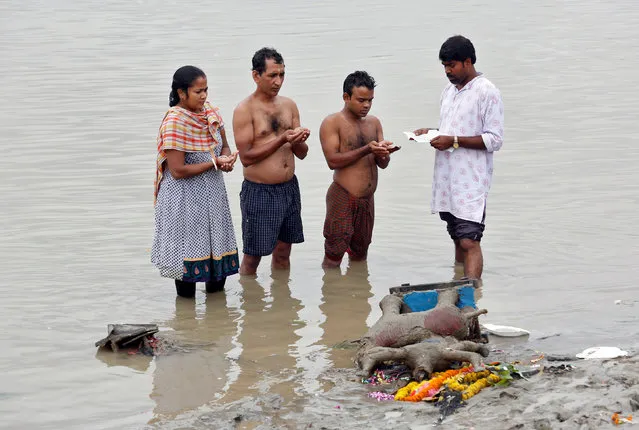 A Hindu priest (R) performs Tarpana, a religious ritual, as he helps a family to pray on the banks of the Ganges river to honour the souls of their departed ancestors during the auspicious day of Mahalaya in Kolkata, September 19, 2017. (Photo by Rupak De Chowdhuri/Reuters)