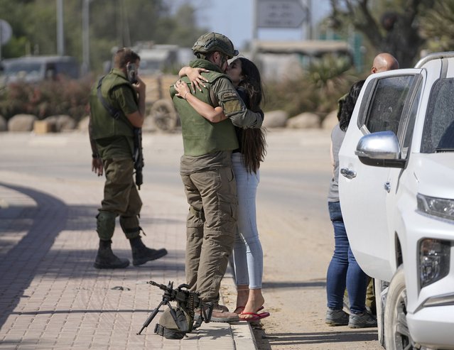 An Israeli soldier kisses his partner as she visits him near the border with the Gaza Strip, southern Israel, Friday, October 20, 2023. The Israeli military has beefed up ground forces near the Gaza Strip ahead of an expected ground invasion as the latest war between Israel and Hamas militants completes its second week. (Photo by Ohad Zwigenberg/AP Photo)