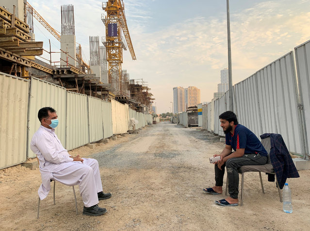 Two guards working at a construction site keep distance during a lockdown to prevent the spread of coronavirus disease (COVID-19) in Dubai, United Arab Emirates on April 18, 2020. (Photo by Ahmed Jadallah/Reuters)