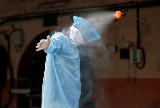 A municipal worker is sanitized after he cremated the body of a man, who died due to coronavirus disease (COVID-19), at a crematorium in Ahmedabad, India, April 22, 2020. (Photo by Amit Dave/Reuters)