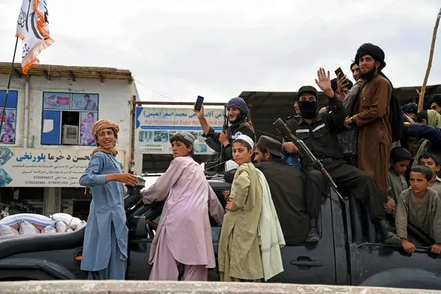 Armed Taliban fighters along with their supporters take part in a parade during the celebrations to mark the first anniversary of the withdrawal of US-led troops from Afghanistan, in Kandahar on August 31, 2022. The Taliban declared on August 31 a national holiday and lit up the capital with coloured lights to celebrate the first anniversary of the withdrawal of US-led troops from Afghanistan after a brutal 20-year war. (Photo by Javed Tanveer/AFP Photo)
