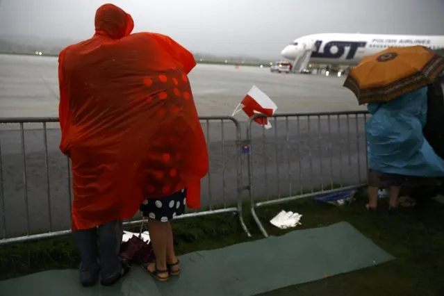 People during heavy rain under raincover wait for Pope Francis farewell ceremony at Balice airport near Krakow, Poland July 31, 2016. (Photo by Kacper Pempel/Reuters)