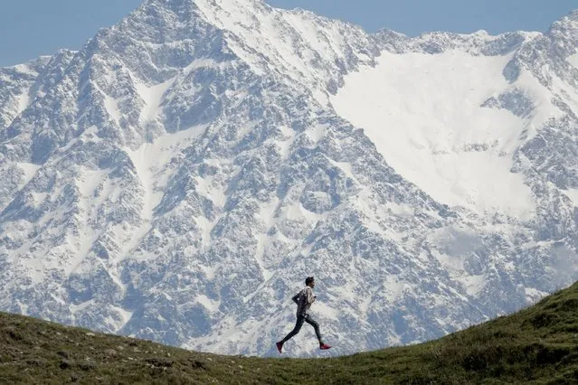 A person runs near the Dhauladhar mountain range at Jalot village, Himachal Pradesh, India, 22 April 2020. Dhauladhar mountain range is part of the lesser Himalayan chain of mountains, with Hanuman Tibb being the highest peak at nearly 6,000 meters. (Photo by Sanjay Baid/EPA/EFE)