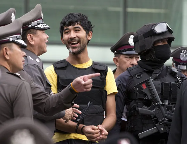 Police officers joke with a key suspect in last month's Bangkok bombing, yellow shirt, identified by Thai police as Yusufu Mierili, also as Yusufu Mieraili, traveling on a Chinese passport, but his nationality remains unconfirmed, around a central Bangkok shopping center during a reenactment for the August 17 bombing at Bangkok's popular Erawan Shrine that left 20 people dead and more than 120 injured, Wednesday, September 9, 2015. (Photo by Mark Baker/AP Photo)