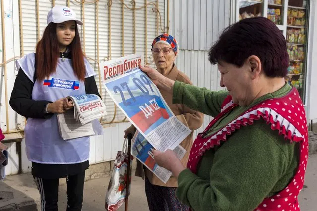 A volunteer of Luhansk regional election commission distributes newspapers to local citizens prior to a referendum in Luhansk, Luhansk People's Republic controlled by Russia-backed separatists, eastern Ukraine, Thursday, September 22, 2022. Authorities in Russian-controlled regions in eastern and southern Ukraine are preparing to hold referendums on becoming part of Russia – a move that could allow Moscow to escalate the war. The votes start Friday in the Luhansk, Kherson and partly Russian-controlled Zaporizhzhia and Donetsk regions. Writing on newspaper reads in Russian “27.09 Yes”. (Photo by AP Photo/Stringer)