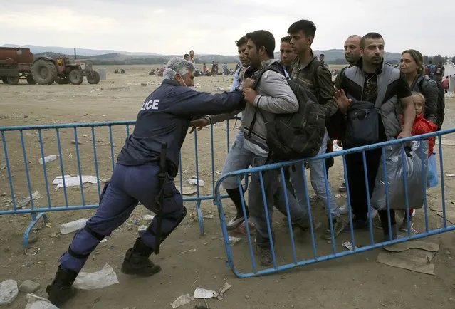 A Greek policeman pushes refugees behind a barrier at Greece's border with Macedonia, near the Greek village of Idomeni, September 9, 2015. Most of the people flooding into Europe are refugees fleeing violence and persecution in their home countries who have a legal right to seek asylum, the United Nations said on Tuesday. (Photo by Yannis Behrakis/Reuters)