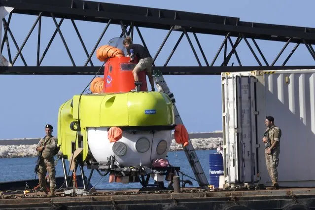 A technical member team of the small, 3-person underwater craft, a Pisces VI submarine, center top, checks the submarine at the Lebanese navy base, in Tripoli, north Lebanon, Friday, August 26, 2022. The Lebanese navy and a submarine crew announced that they found the remains of at least seven of the approximately 30 drowned migrants in a sunken ship off the coast of Tripoli. In late April, a boat carrying about 80 Lebanese, Syrians, and Palestinians trying to migrate by sea to Italy sunk following a confrontation with the Lebanese navy. (Photo by Hussein Malla/AP Photo)