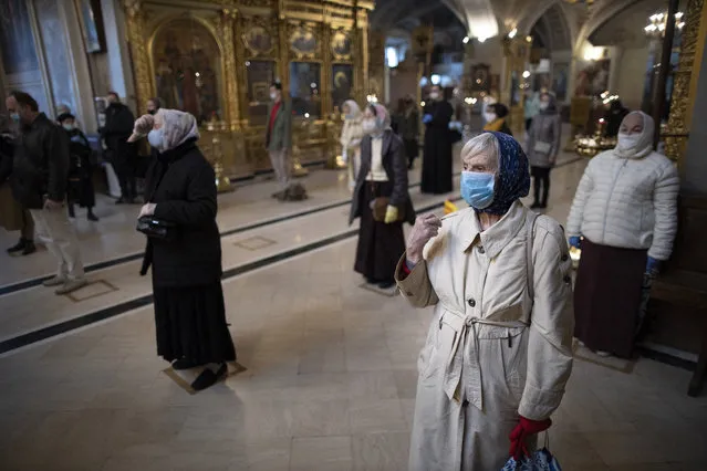 Parishioners wearing face masks to protect against coronavirus, observe social distancing guidelines cross themselves as they attend service at the Epiphany Cathedral in Moscow, Russia, Tuesday, June 2, 2020. Churches in Moscow reopen to believers after a two-month lockdown imposed to control the spread of the coronavirus. (Photo by Alexander Zemlianichenko/AP Photo)