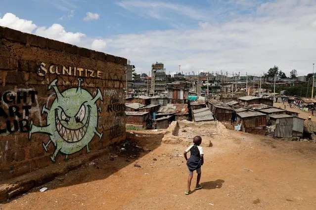 A boy walks in front of a graffiti promoting the fight against the coronavirus disease (COVID-19) in the Mathare slums of Nairobi, Kenya, May 22, 2020. (Photo by Baz Ratner/Reuters)
