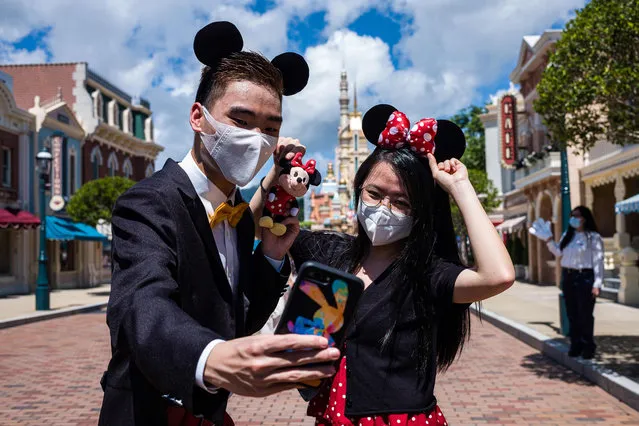 Visitors dressed in costumes take a selfie at Hong Kong's Disneyland on June 18, 2020, after the theme park officially reopened following nearly five months of closure in a fresh boost for a city that has largely managed to defeat the COVID-19 coronavirus. (Photo by Anthony Wallace/AFP Photo)