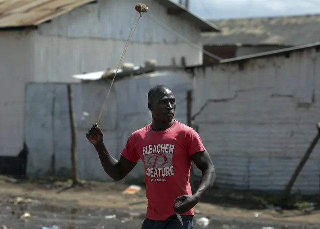 An opposition supporter hurls a stone during clashes with police in the Jacaranda grounds quarter in Nairobi, Kenya, Tuesday, November 28, 2017. (Photo by Brian Inganga/AP)