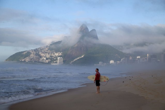 As the first beams of sunlight fall over the favela of Vidigal, a surfer eyes the waves at sunrise on Christmas morning at Ipanema Beach in Rio De Janeiro, Brazil on December 25, 2024. (Photo by Bob Karp/ZUMA Press Wire/Rex Features/Shutterstock)