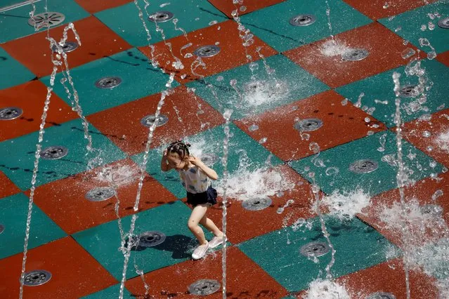 A girl plays with water on a summer day at a shopping complex in Beijing, China on July 14, 2020. (Photo by Tingshu Wang/Reuters)