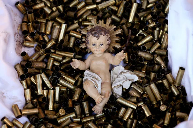A statue of the baby Jesus on a bed of bullet shells is seen in a Nativity scene outside the Basilica of St Francis in Assisi, Italy, December 21, 2017. The 445 shells represent the number of priests, nuns, monks and religious teachers killed for their faith since 2000. Picture taken December 21, 2017. (Photo by Alessandro Bianchi/Reuters)