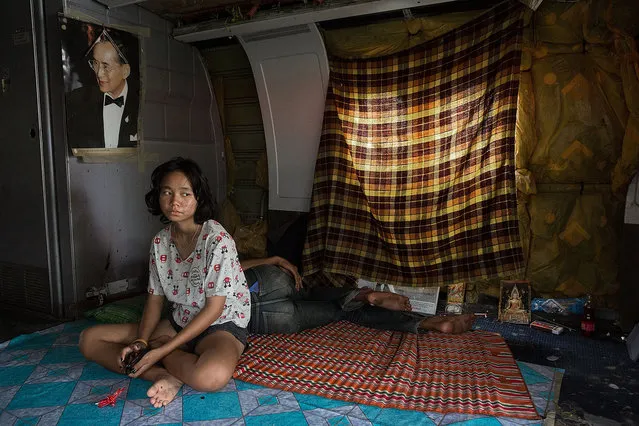 A young Thai woman sits under a picture of the king in her home in a disused airplane on September 12, 2015 in Bangkok, Thailand. (Photo by Taylor Weidman/Getty Images)