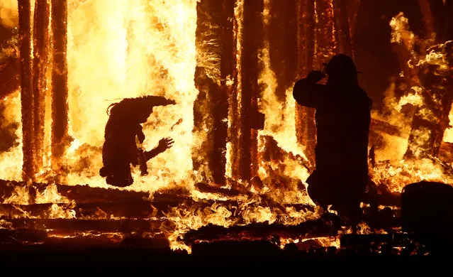 A Burning Man participant (L) evades a chasing firefighter and falls into the flames of the “Man Burn” after evading the attempted tackles of multiple rangers and law enforcement personnel at the annual Burning Man arts and music festival in the Black Rock Desert of Nevada, September 3, 2017. (Photo by Jim Bourg/Reuters)