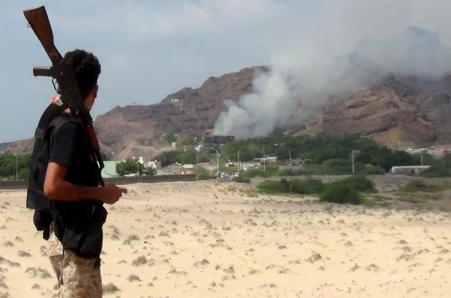 A militant loyal to Yemen's government looks as smoke billows from al-Qasr hotel after it was hit by explosions in the western suburbs of Yemen's southern port city of Aden, October 6, 2015. Unidentified assailants fired missiles at an Aden hotel housing Yemeni officials and at a Gulf military base in Aden on Tuesday, a government spokesman and residents said, in the biggest attack on the government since it retook the city from Houthi foes in July. (Photo by Reuters/Stringer)
