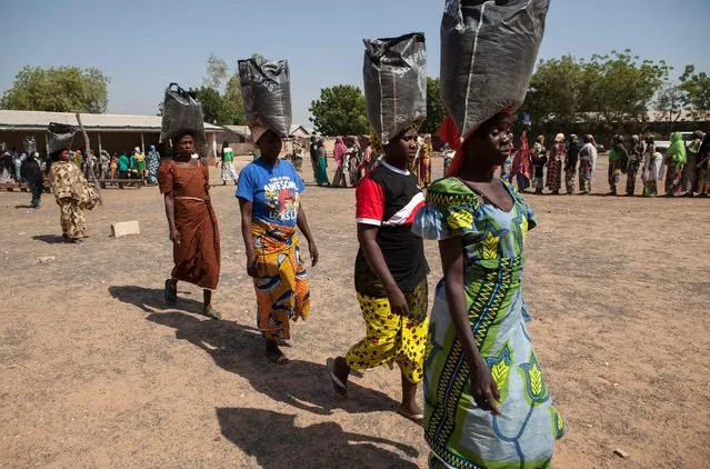 This file photo taken on December 4, 2014 shows displaced women carrying sacks of food aid received during a distribution at the Cathedral of Yola, state capital of Adamawa, Nigeria. (Photo by Florian Plaucheur/AFP Photo)