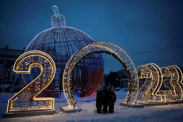 A family poses for a picture in front of Christmas and New Year decorations in Moscow on December 19, 2022. (Photo by Natalia Kolesnikova/AFP Photo)