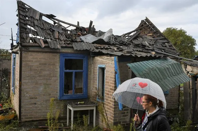 Local resident Ekaterina, 22, stands next to her residential building that was damaged after an overnight Russian attack in Kramatorsk, Ukraine, Tuesday, October 4, 2022. (Photo by Andriy Andriyenko/AP Photo)