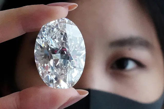 An employee of Sotheby's poses with a perfect 100+ carat diamond, the second largest oval diamond of its kind to ever appear at an auction which will be auctioned by Sotheby's in Hong Kong in October, in the Manhattan borough of New York City, New York, U.S., September 9, 2020. (Photo by Carlo Allegri/Reuters)