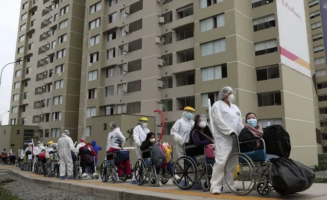 Health workers wheel out a group of about 80 COVID patients who have been discharged and are being released from the former Athletes Village built for Lima's Panamerican Games, which is used as a temporary hospital treating hundreds of COVID-19 patients in Lima, Peru, Monday, September 21, 2020. (Photo by Martin Mejia/AP Photo)