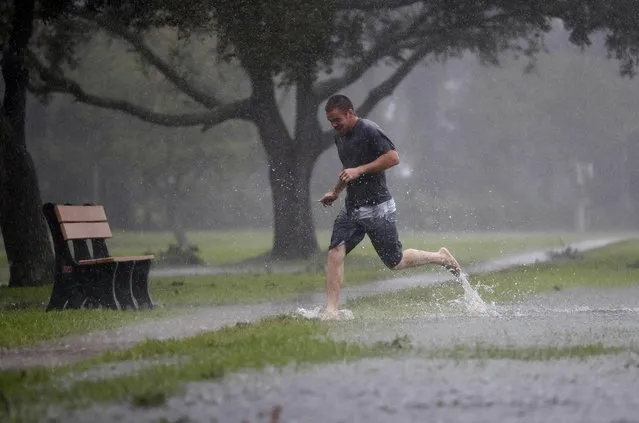 Austin Massett runs through a area beginning to flood as Hurricane Matthew moves closer to St. Augustine, Fla., Friday, October 7, 2016. Matthew was downgraded to a Category 3 hurricane overnight, and its storm center hung just offshore as it moved up the Florida coastline, sparing communities its full 120 mph winds. (Photo by John Bazemore/AP Photo)