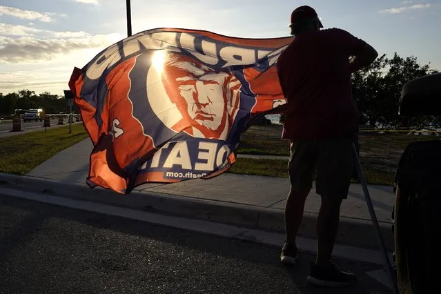 A supporter of former President Donald Trump unfurls a flag outside of Trump's Mar-a-Lago estate, Monday, March 20, 2023, in Palm Beach, Fla. (Photo by Lynne Sladky/AP Photo)