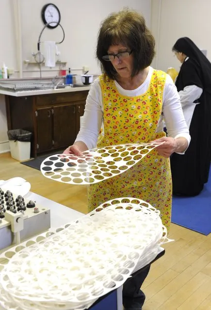 Lay worker Cindy Welch stacks the waste from a sheet of low-gluten prayer bread after the wafers were punched out with a dye cutter machine at the Benedictine Sisters of Perpetual Adoration monastery in Clyde, Missouri, December 18, 2014. (Photo by Dave Kaup/Reuters)
