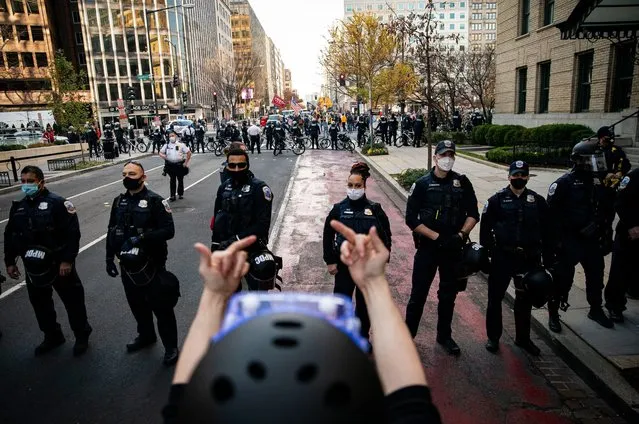 A demonstrator gestures as members of the Metropolitan Police Department stand guard as they separate counter-protesters from supporters of President Trump near Black Lives Matter Plaza, on December 12, 2020 in Washington, DC. Thousands of protesters who refuse to accept that President-elect Joe Biden won the election are rallying ahead of the electoral college vote to make Trump's 306-to-232 loss official. (Photo by Al Drago/Getty Images)