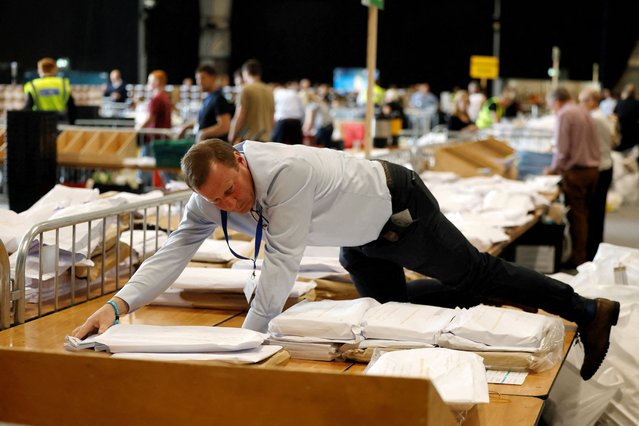 An electoral worker climbs onto a table as European and local ballot papers are separated before starting the count, at a local election counting centre, in Dublin, Ireland, on June 8, 2024. (Photo by Clodagh Kilcoyne/Reuters)