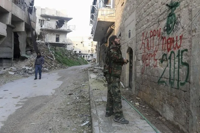 A “Free Syrian Army” fighter sprays graffiti on a wall prior to the new year in Aleppo December 31, 2014. (Photo by Jalal Al-Mamo/Reuters)
