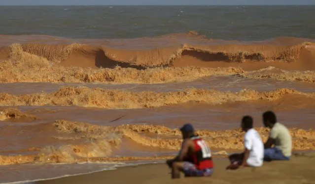 Men look on from the banks of Rio Doce (Doce River), which was flooded with mud after a dam owned by Vale SA and BHP Billiton Ltd burst, as the river joins the sea on the coast of Espirito Santo in Regencia Village, Brazil, November 22, 2015. (Photo by Ricardo Moraes/Reuters)