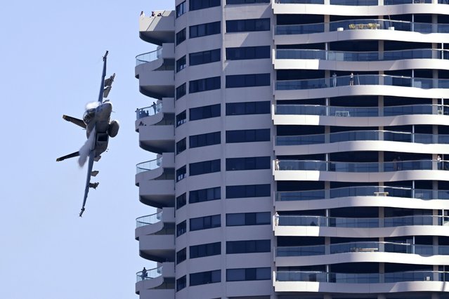 People stand on balconies of a high rise building as a Royal Australian Air Force F/A-18F Super Hornet conducts a flight in the lead-up to the Brisbane Festival's Riverfire in Brisbane, Friday, August 30, 2024. (Photo by Darren England/AAP Image via AP Photo)