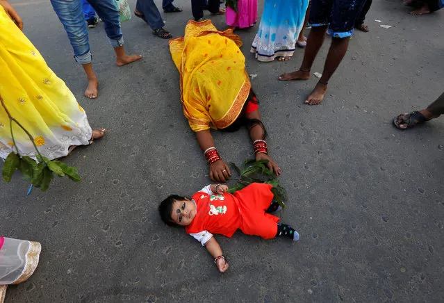 A Hindu devotee lies on a road before stepping over the child in a ritual to seek blessings from the Sun god during the religious festival of Chhat Puja in Kolkata, India, November 6, 2016. (Photo by Rupak De Chowdhuri/Reuters)